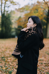 穿黑色大衣和围巾的女孩，在深秋落叶森林里