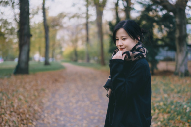 穿黑色大衣和围巾的女孩，在深秋落叶森林里