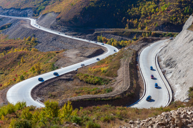 秋天盘山公路U形弯道中行驶的车队