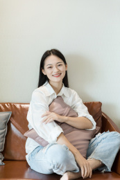 年轻女性坐在沙发上看镜头微笑