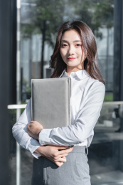 抱着电脑内胆包的亚洲商务女性在户外