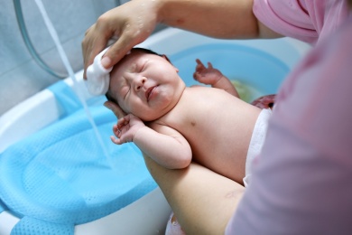 专业的月嫂正在给可爱的新生婴儿洗澡