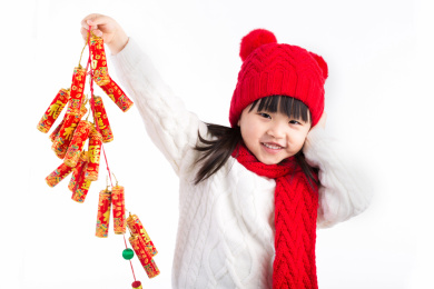 带红帽的小女孩一手捂耳朵一手提鞭炮