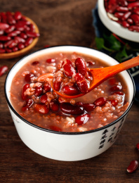 深底上放着一碗红芸豆营养粥和勺子上挖着粥