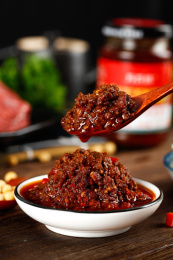 深底上放着一碟香辣牛肉酱和勺子上挖着酱