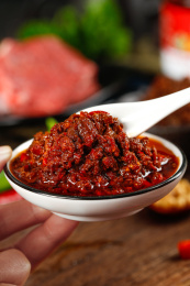 手上端着一碟下饭牛肉酱和勺子上挖着牛肉酱