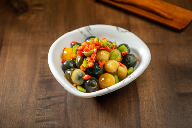 棕色木纹桌上放着一盘巧拌小皮蛋   