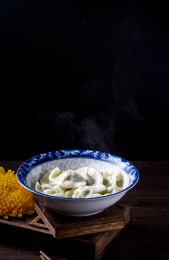 棕色木桌上一碗热气腾腾的中国传统食物饺子