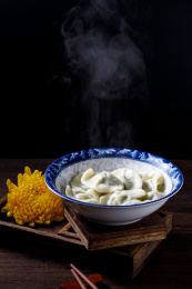 棕色木桌上一碗热气腾腾的中国传统食物饺子