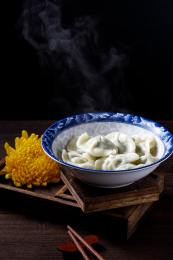 棕色木桌上一碗热气腾腾的中国传统食物饺子