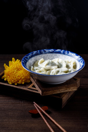 棕色木桌上一碗热气腾腾的中国传统食物饺子