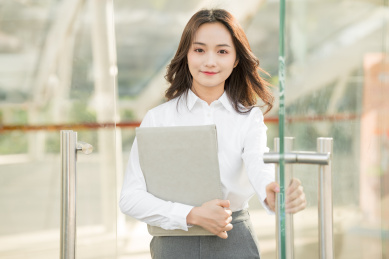 商务女性抱着笔记本电脑推开门