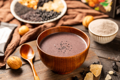 木板背景上一碗核桃芝麻黑豆粉糊