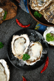 黑底上盘子里放着两个鲜冻生蚝