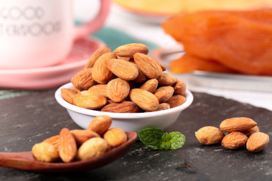 黑底上放着一碟扁桃仁和勺子上挖着巴旦木仁