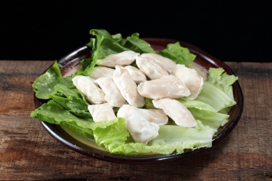 黑圆盘里生菜上的冷冻虾饺