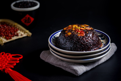 黑色背景上放在中式瓷盘里的黑糯米八宝饭