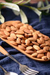 桌面上的木盘子里的香脆可口的杏仁