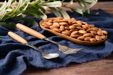 桌面上的木盘子里的香脆可口的杏仁