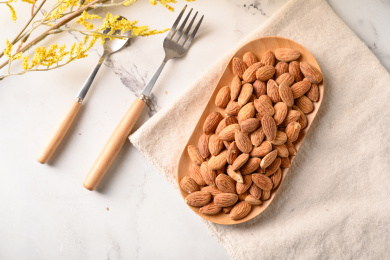 桌面上的木盘子里的香脆可口的杏仁