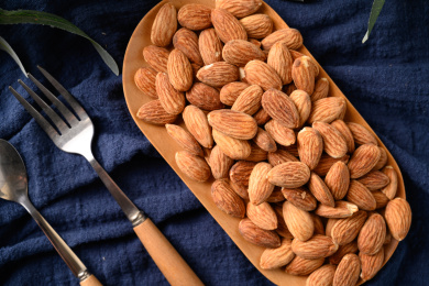 桌面上的木盘子里的香脆可口的杏仁