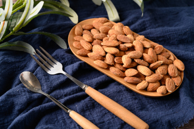 桌面上的木盘子里的香脆可口的杏仁