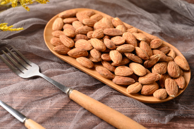 桌面上的木盘子里的香脆可口的杏仁