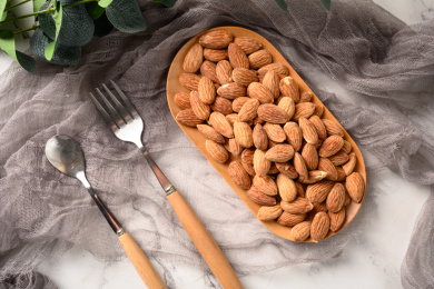 桌面上的木盘子里的香脆可口的杏仁