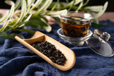 桌面上的木盘子里的乌龙茶叶和玻璃杯里的乌龙茶
