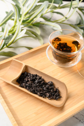 桌面上的木盘子里的乌龙茶叶和玻璃杯里的乌龙茶