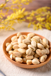 桌面上的木纹盘子里面的香脆的开心果