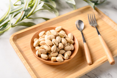 桌面上的木纹盘子里面的香脆的开心果