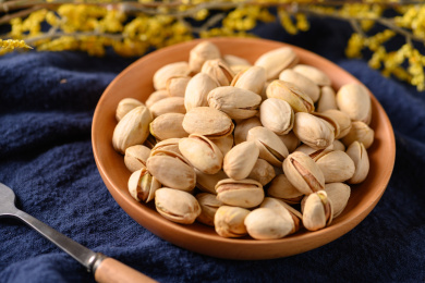 桌面上的木纹盘子里面的香脆的开心果