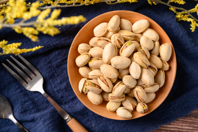 桌面上的木纹盘子里面的香脆的开心果