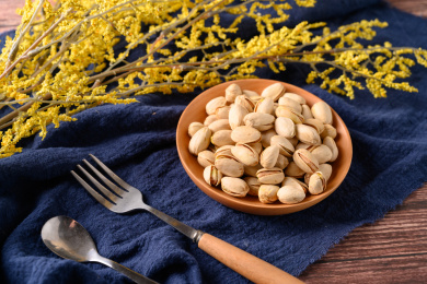 桌面上的木纹盘子里面的香脆的开心果