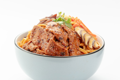 大碗里正在淋酱的蔬菜牛肉干拌面