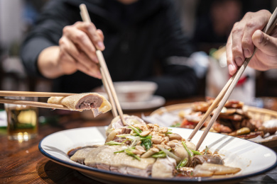 几个人用筷子夹餐桌上的白切鸡