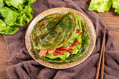 木板背景上一盘菠菜味手抓饼
