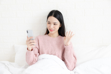 一名年轻女性在卧室里用手机进行视频通话