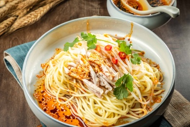 棕色木纹桌上放着一盘鸡丝凉面