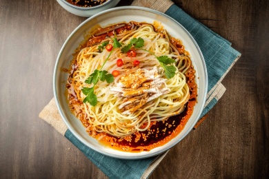 棕色木纹桌上放着一盘鸡丝凉面