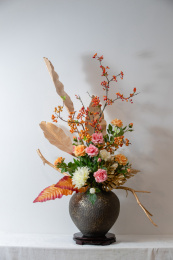 浅色背景深色花瓶上一束盛开花朵的插花装饰