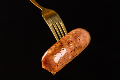 黑色背景里刀叉着一根藤椒烤肠