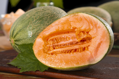 木板上放着一个完整的网纹瓜和半边哈密瓜