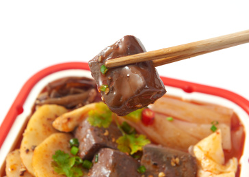 白色背景上摆放的牛油鸭血火腿自热小火锅