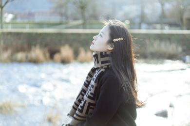坐在清澈河水边的可爱女孩，人像特写