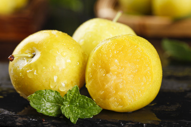 黑底上放着两个蜂糖李子和一个咬过李子