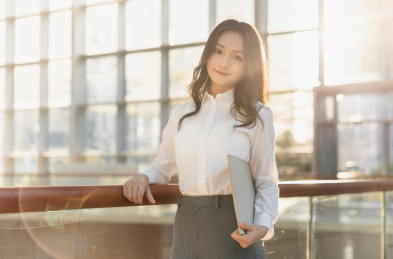 亚洲商务人士拿着手提电脑倚靠在栏杆旁