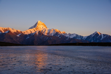 积雪覆盖的中国贡嘎雪山，与结冰的蓝色湖面
