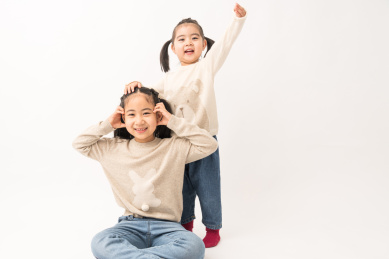 两名坐在白色背景前玩耍的姐妹